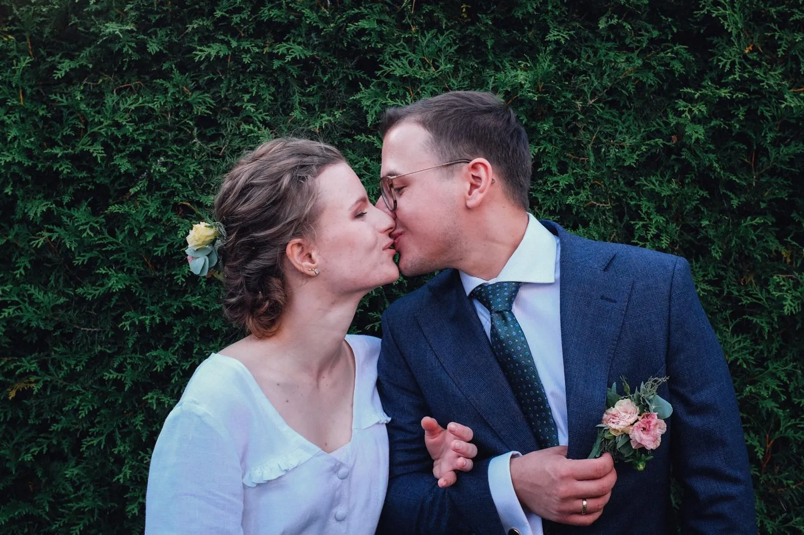 Pocałunek pary młodej na tle zieleni, intymny portret ślubny.